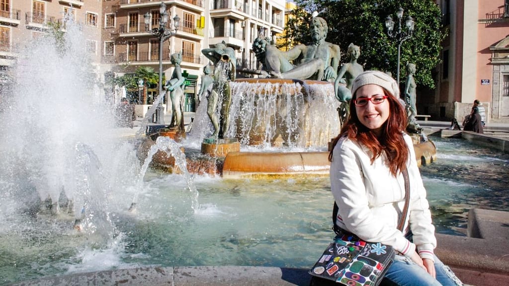 Io seduta sul bordo di una fontana a Valencia. Slow travel.